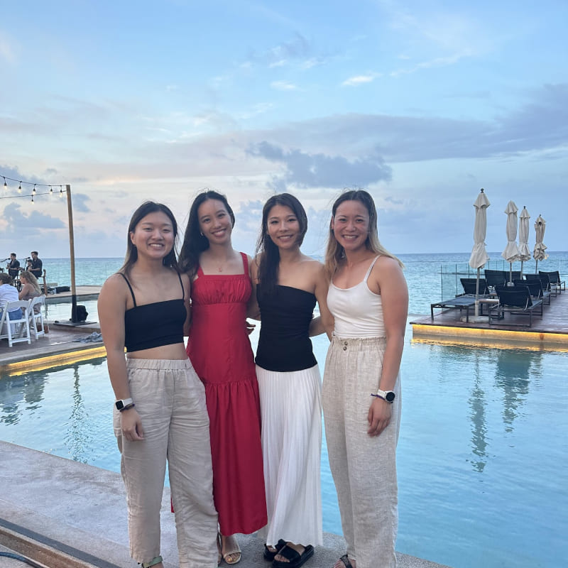 four women in front of a pool with a nice sunset in the back