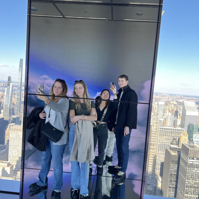 Four people in a mirror with clouds in the background