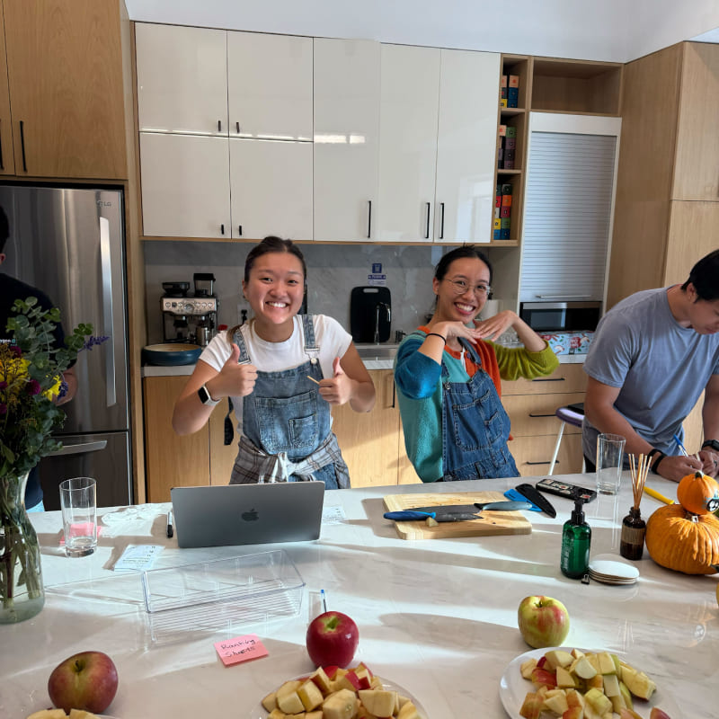 Two girls wearing overalls in front of a plate of apple slices