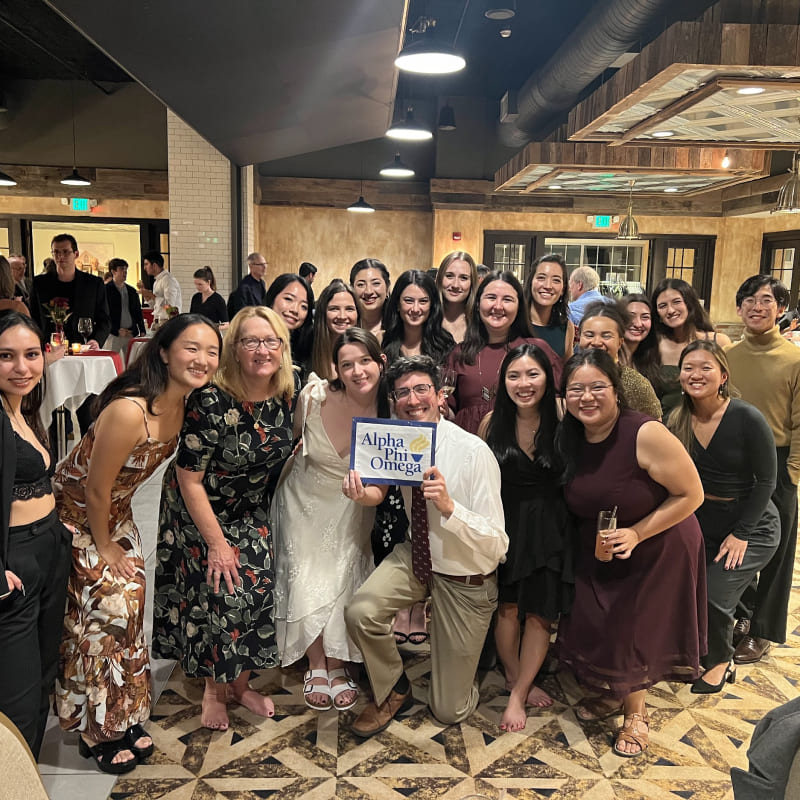 A group picture with someone holding an Alpha Phi Omega sign