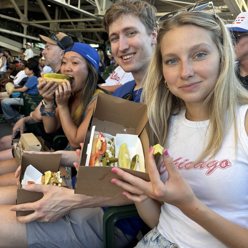 Emily, Ian, and Cindy holding Chicago-style hotdogs at a baseball game