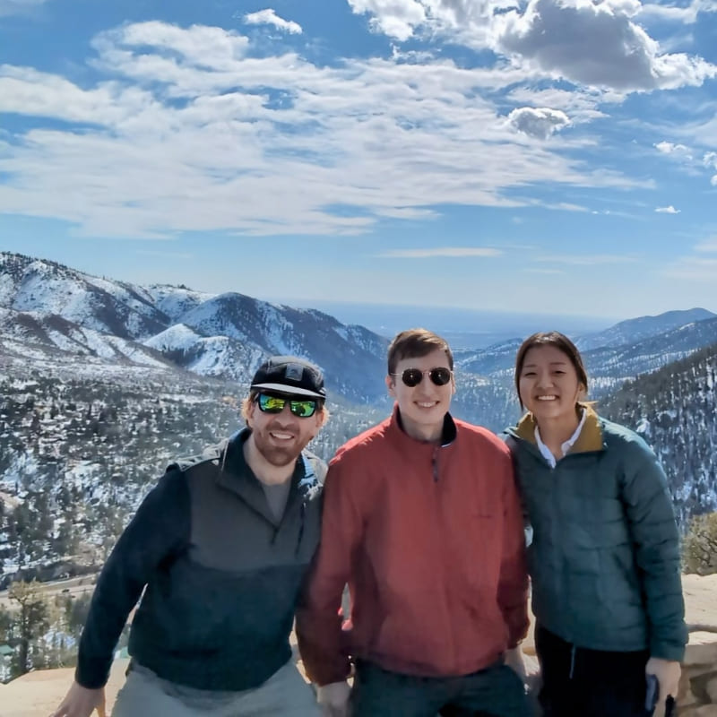 3 people at the top of a snowy mountain